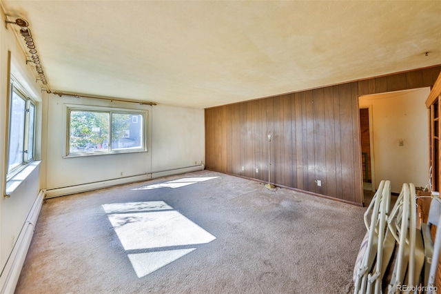 unfurnished room with light carpet, wood walls, and a baseboard radiator