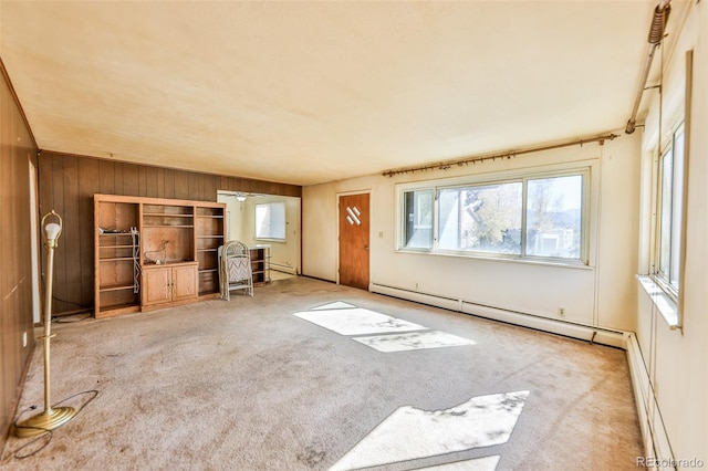 unfurnished living room with carpet floors, wooden walls, and baseboard heating