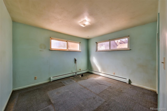 spare room featuring baseboards, baseboard heating, and dark colored carpet