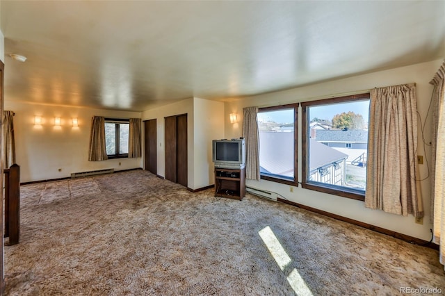 unfurnished living room with carpet flooring and a baseboard heating unit