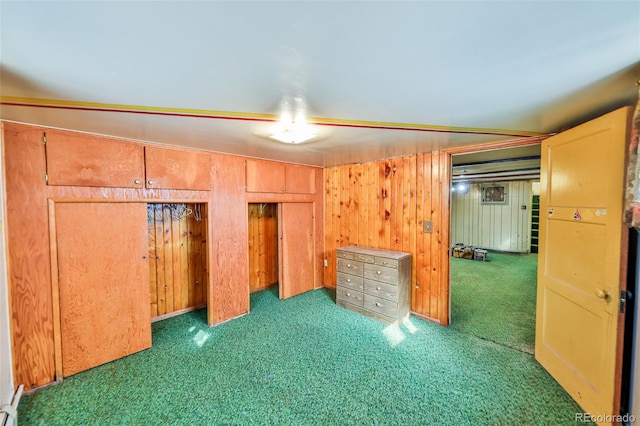 unfurnished bedroom featuring wood walls and dark colored carpet