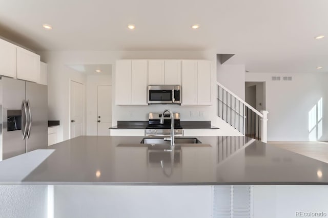 kitchen with white cabinets, sink, stainless steel appliances, and a kitchen island with sink