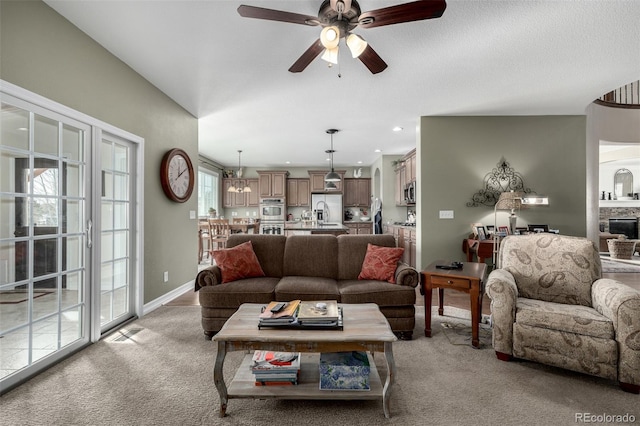 living area featuring light carpet, baseboards, ceiling fan, a stone fireplace, and recessed lighting