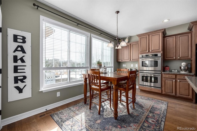 dining room featuring visible vents, baseboards, a notable chandelier, and wood finished floors