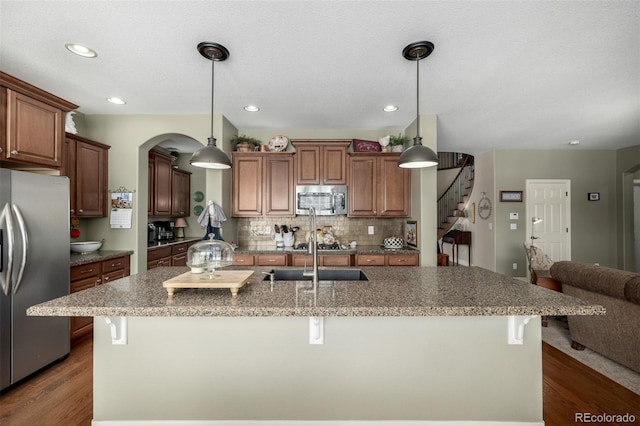 kitchen with a breakfast bar area, appliances with stainless steel finishes, decorative backsplash, and a sink