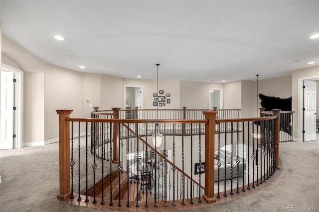 hall featuring carpet floors, recessed lighting, baseboards, and an upstairs landing