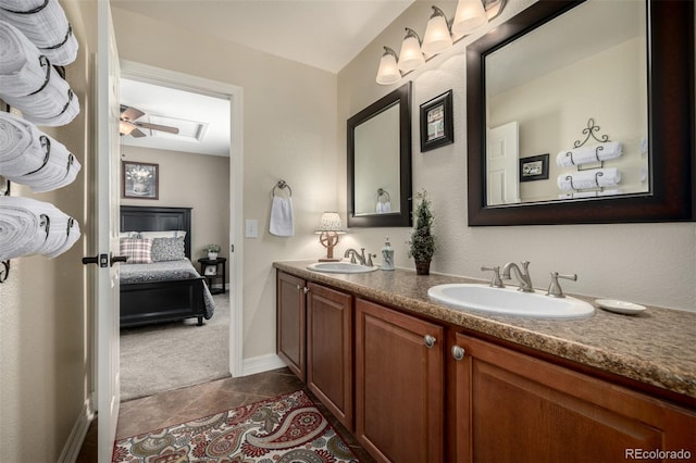 ensuite bathroom with ceiling fan, double vanity, a sink, and tile patterned floors