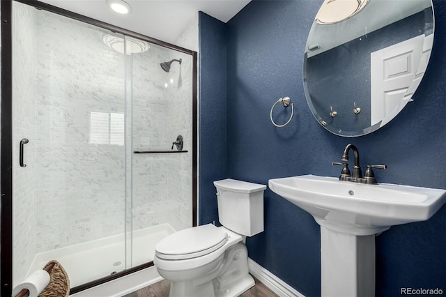 full bath featuring toilet, a shower stall, and baseboards