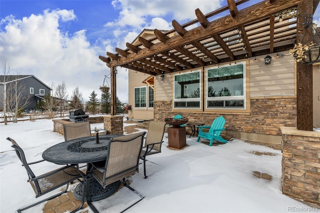 snow covered patio with outdoor dining area and a pergola