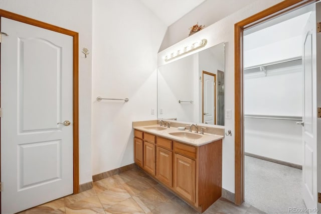 full bathroom with double vanity, baseboards, and a sink