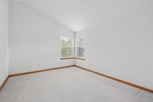unfurnished room with light colored carpet, baseboards, and vaulted ceiling