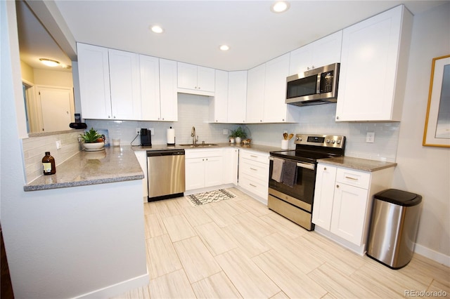 3111 W Bails Pl, Denver, CO 80219 - kitchen with appliances with stainless steel finishes, decorative backsplash, white cabinets, light stone counters, and recessed lighting