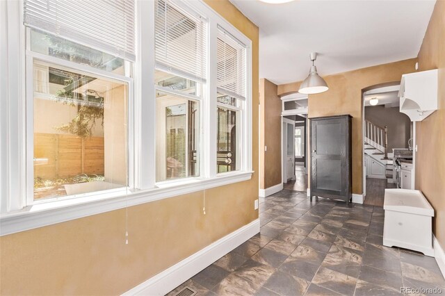 368 S Humboldt St, Denver, CO 80209 - hall featuring baseboards, dark stone finish floors, arched walkways, and stairway