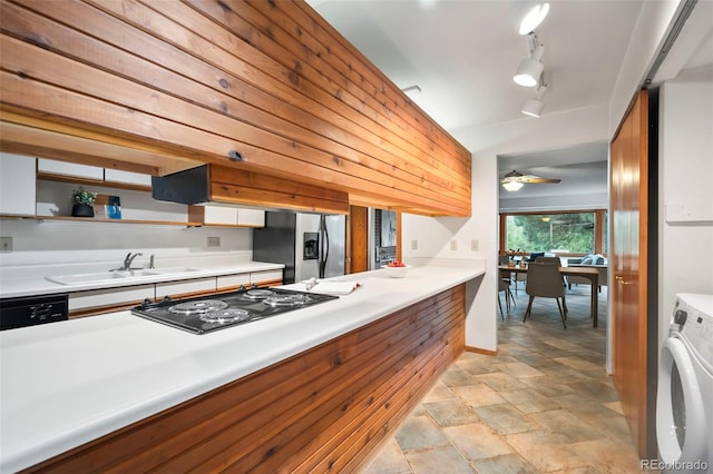 kitchen with a sink, washer / clothes dryer, light countertops, black appliances, and open shelves