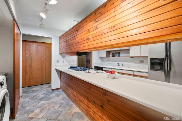 kitchen with a sink, washer / clothes dryer, light countertops, appliances with stainless steel finishes, and white cabinetry