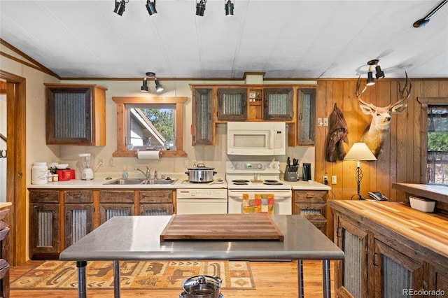 kitchen with wood walls, crown molding, white appliances, and sink