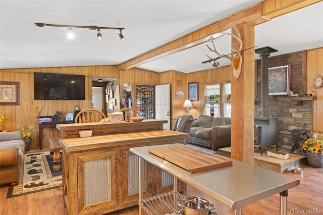 kitchen featuring light hardwood / wood-style floors, a wood stove, lofted ceiling, and wood walls