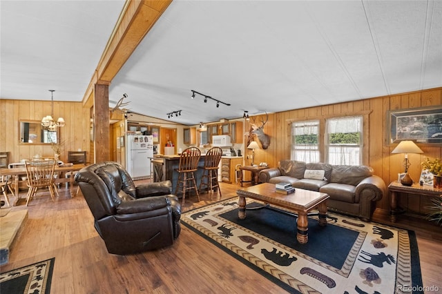 living room featuring hardwood / wood-style flooring, lofted ceiling, rail lighting, and a chandelier