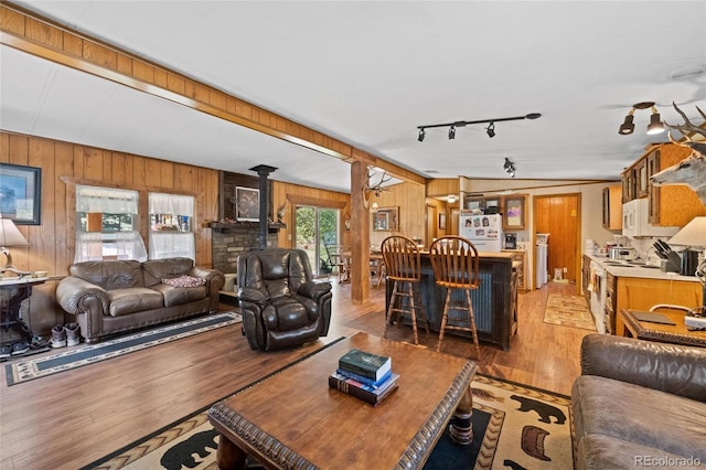 living room featuring a wood stove, wood walls, hardwood / wood-style floors, and rail lighting