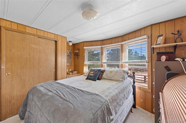 carpeted bedroom with wooden walls, a closet, and a textured ceiling