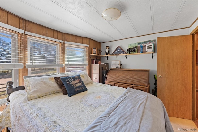 bedroom featuring a textured ceiling, wood walls, and crown molding