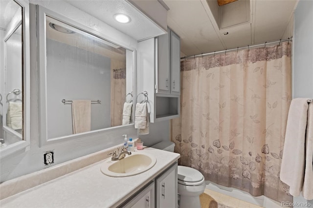 bathroom with vanity, curtained shower, toilet, and a textured ceiling