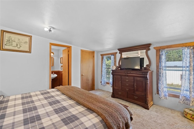 carpeted bedroom featuring lofted ceiling and ensuite bath