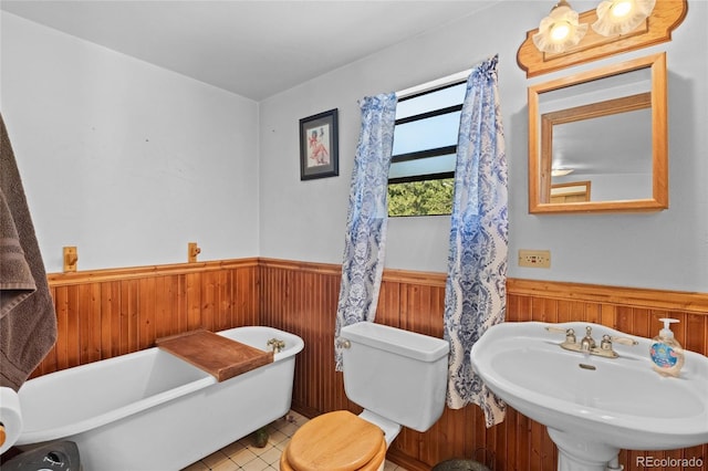 bathroom featuring tile patterned floors, sink, wooden walls, toilet, and a tub