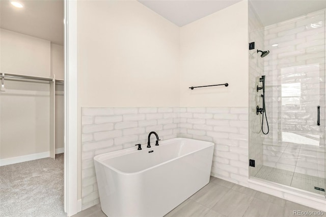 bathroom featuring tile patterned floors, independent shower and bath, and tile walls