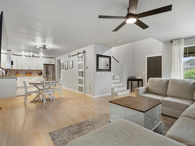23222 E Orchard Pl, Aurora, CO 80015 - living area with a barn door, ceiling fan, light wood-style floors, and stairway