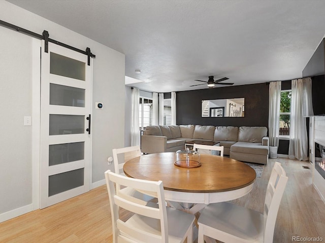 23222 E Orchard Pl, Aurora, CO 80015 - dining room featuring a barn door, a ceiling fan, and light wood-style flooring