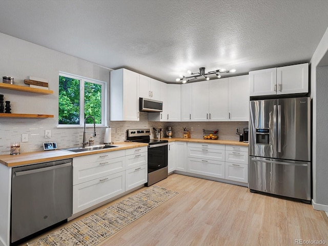 23222 E Orchard Pl, Aurora, CO 80015 - kitchen with stainless steel appliances, wood counters, tasteful backsplash, white cabinetry, and a textured ceiling