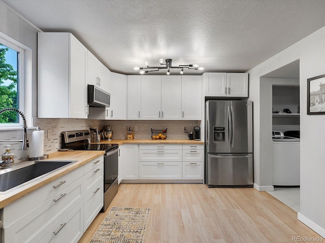 23222 E Orchard Pl, Aurora, CO 80015 - kitchen with stainless steel appliances, backsplash, white cabinetry, light wood-type flooring, and a textured ceiling