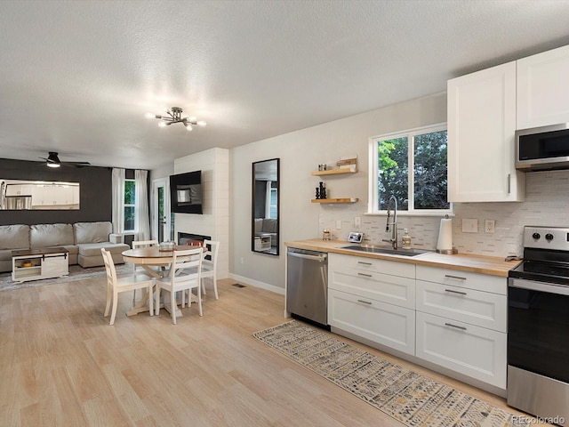 23222 E Orchard Pl, Aurora, CO 80015 - kitchen with stainless steel appliances, butcher block counters, tasteful backsplash, light wood-style floors, and a textured ceiling