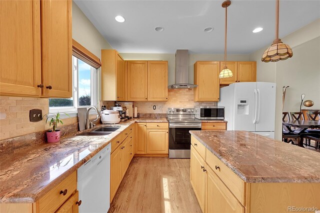 kitchen featuring appliances with stainless steel finishes, wall chimney range hood, sink, and backsplash