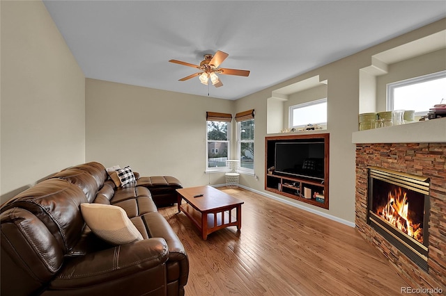 living room featuring ceiling fan, light hardwood / wood-style flooring, and a fireplace