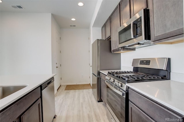 kitchen featuring dark brown cabinetry, light wood finished floors, visible vents, appliances with stainless steel finishes, and light countertops