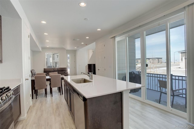 kitchen with an island with sink, appliances with stainless steel finishes, light countertops, and a sink