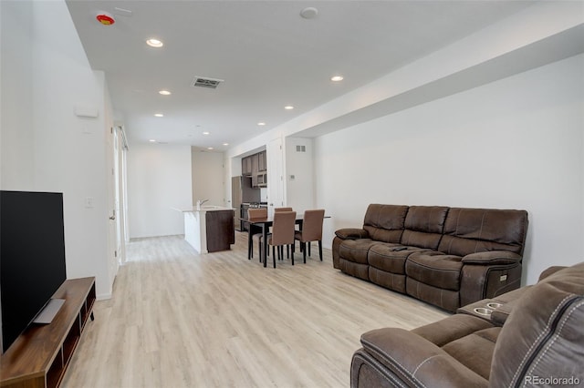 living room featuring light wood-type flooring, visible vents, and recessed lighting