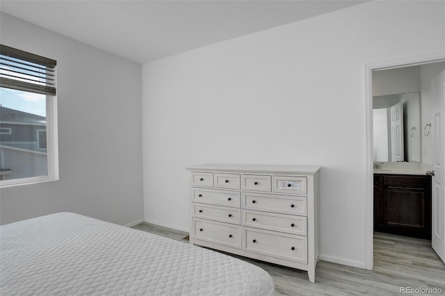 bedroom featuring light wood-type flooring, a sink, and baseboards