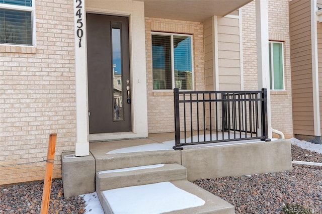 property entrance with covered porch and brick siding