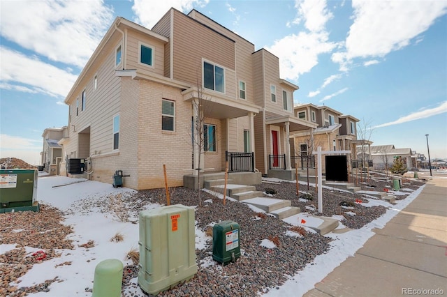 view of front of home featuring a residential view, brick siding, and cooling unit