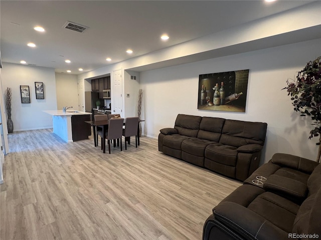 living room featuring recessed lighting, visible vents, light wood-style flooring, and baseboards