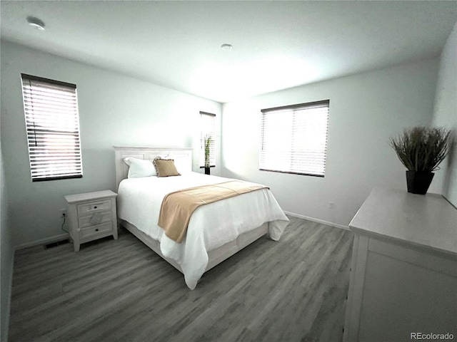 bedroom with dark wood-style floors, baseboards, and visible vents