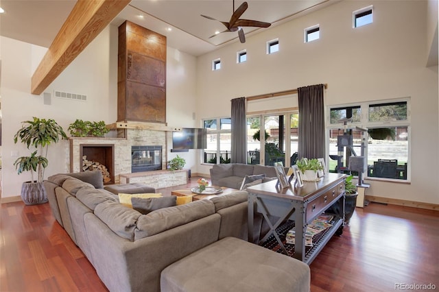 living room featuring a towering ceiling, beamed ceiling, dark hardwood / wood-style floors, and a large fireplace