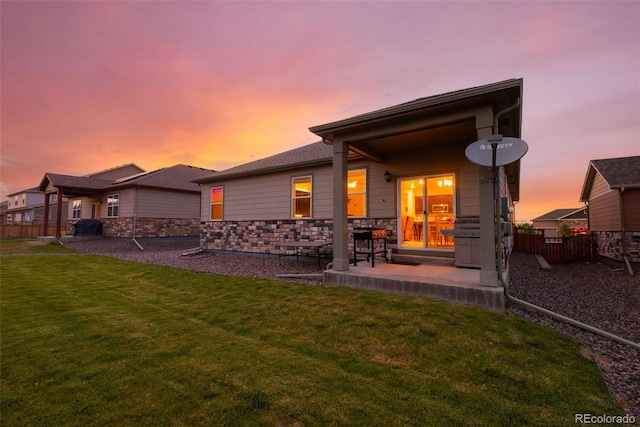 19468 E 65th Pl, Aurora, CO 80019 - back of house at dusk with a patio area and stone siding