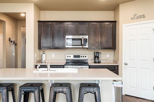 19468 E 65th Pl, Aurora, CO 80019 - kitchen featuring stainless steel appliances, a breakfast bar, and dark brown cabinets