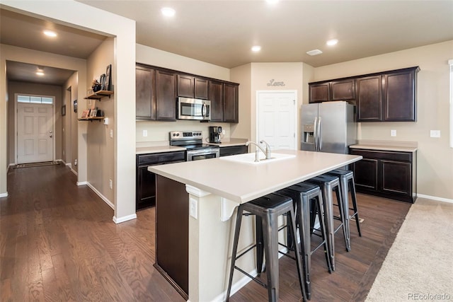 19468 E 65th Pl, Aurora, CO 80019 - kitchen with appliances with stainless steel finishes, a sink, dark brown cabinets, baseboards, and a breakfast bar