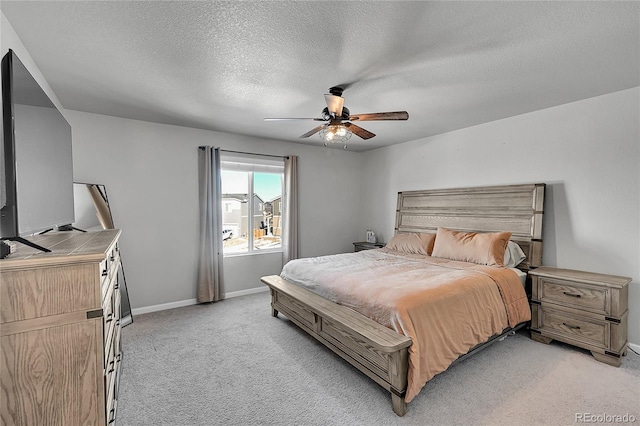 bedroom featuring ceiling fan, light carpet, and a textured ceiling