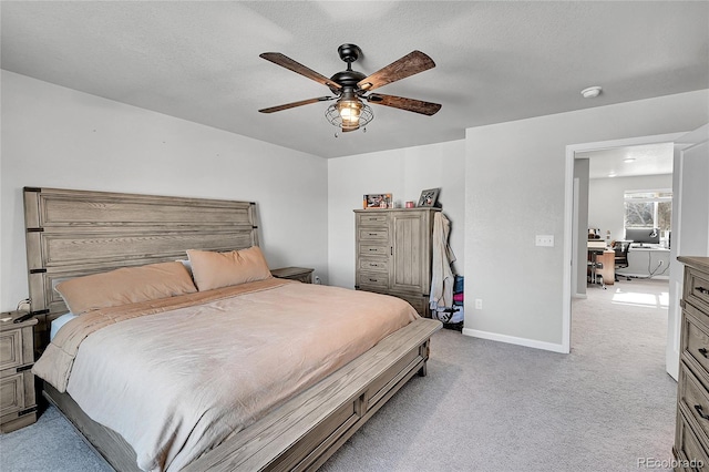 bedroom featuring ceiling fan, light colored carpet, and a textured ceiling